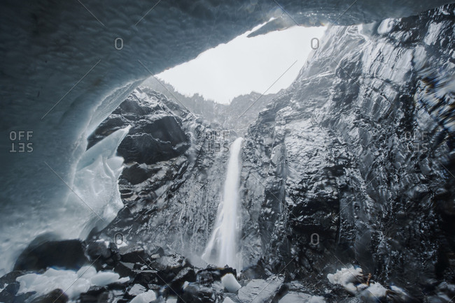 Low angle view of waterfall against sky seen through ice cave