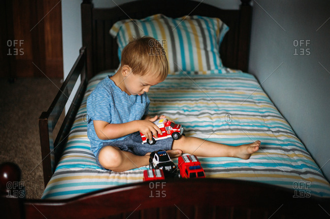 Boy plays with toys on his bed