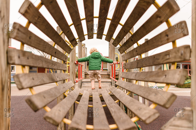 Boy in green coat playing on playground