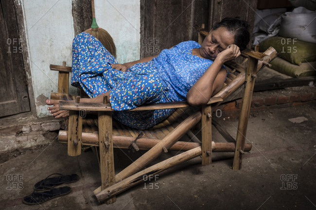 Bagan, Myanmar - September 28, 2016: Woman sleeping on a wood chair at Nyaung U market