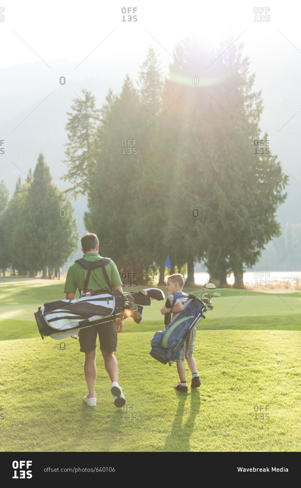 Father and son walking with golf bag on a sunny day