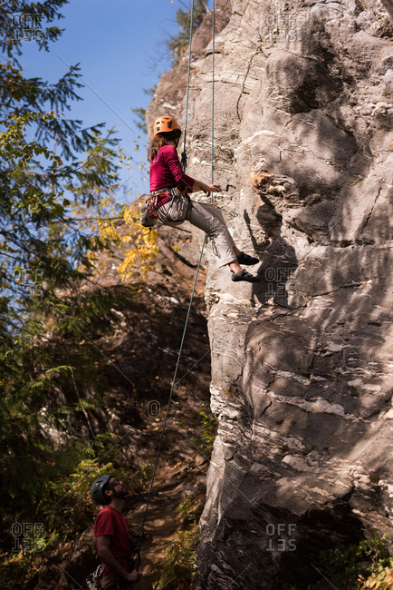 Female climber struggling up the rocky mountain on a sunny day
