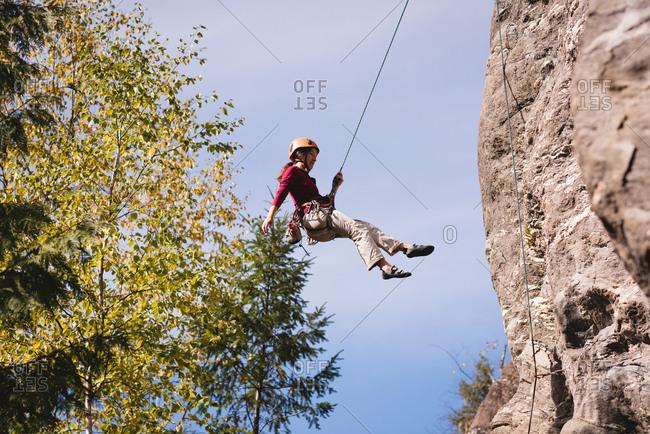 Female climber struggling up the rocky mountain on a sunny day