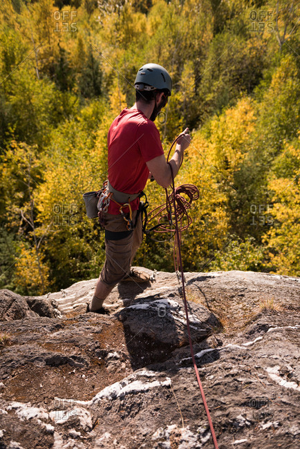 Hiker gathering rope while standing on the mountain in the forest