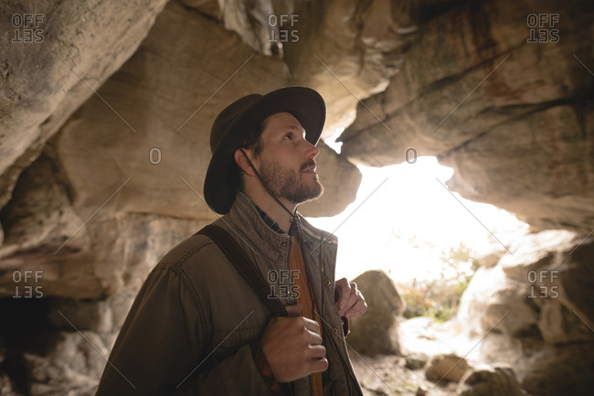 Hiker inspecting rocks in a cave on a sunny day