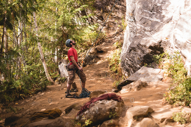 Hiker preparing himself to climb the rocky mountain in forest