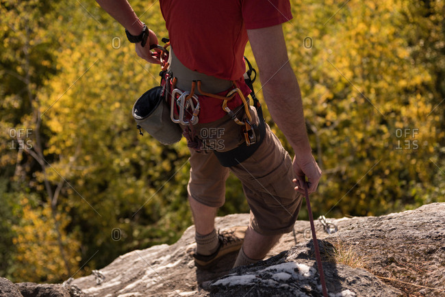 Low section of hiker standing with hiking pole on rocky mountain
