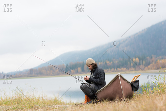 Man sitting on boat outside river with his fishing equipment
