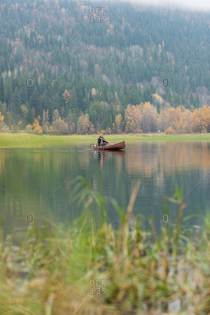 Man rowing canoe in silent river on sunny day