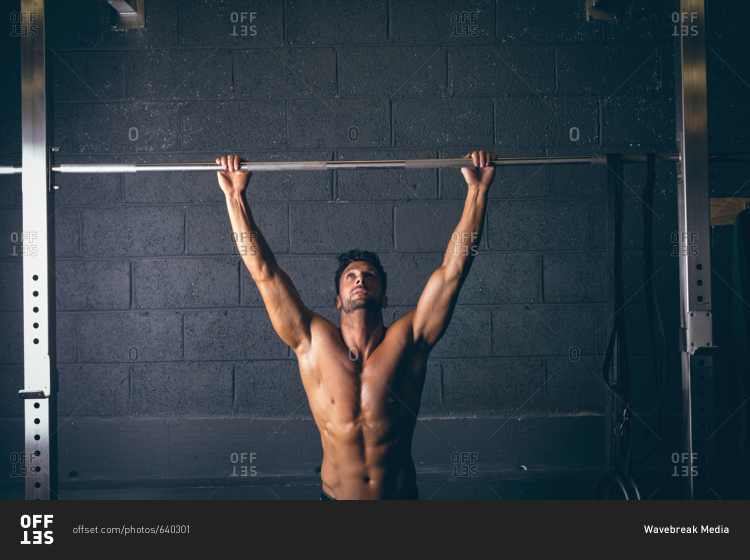 Muscular man exercising on pull-up bar in the fitness studio