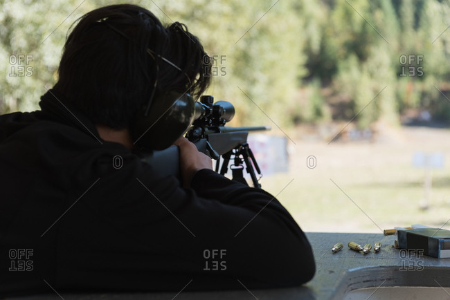 Man aiming sniper rifle at target in shooting range