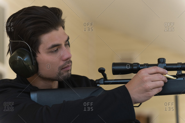 Man loading bullet into sniper rifle