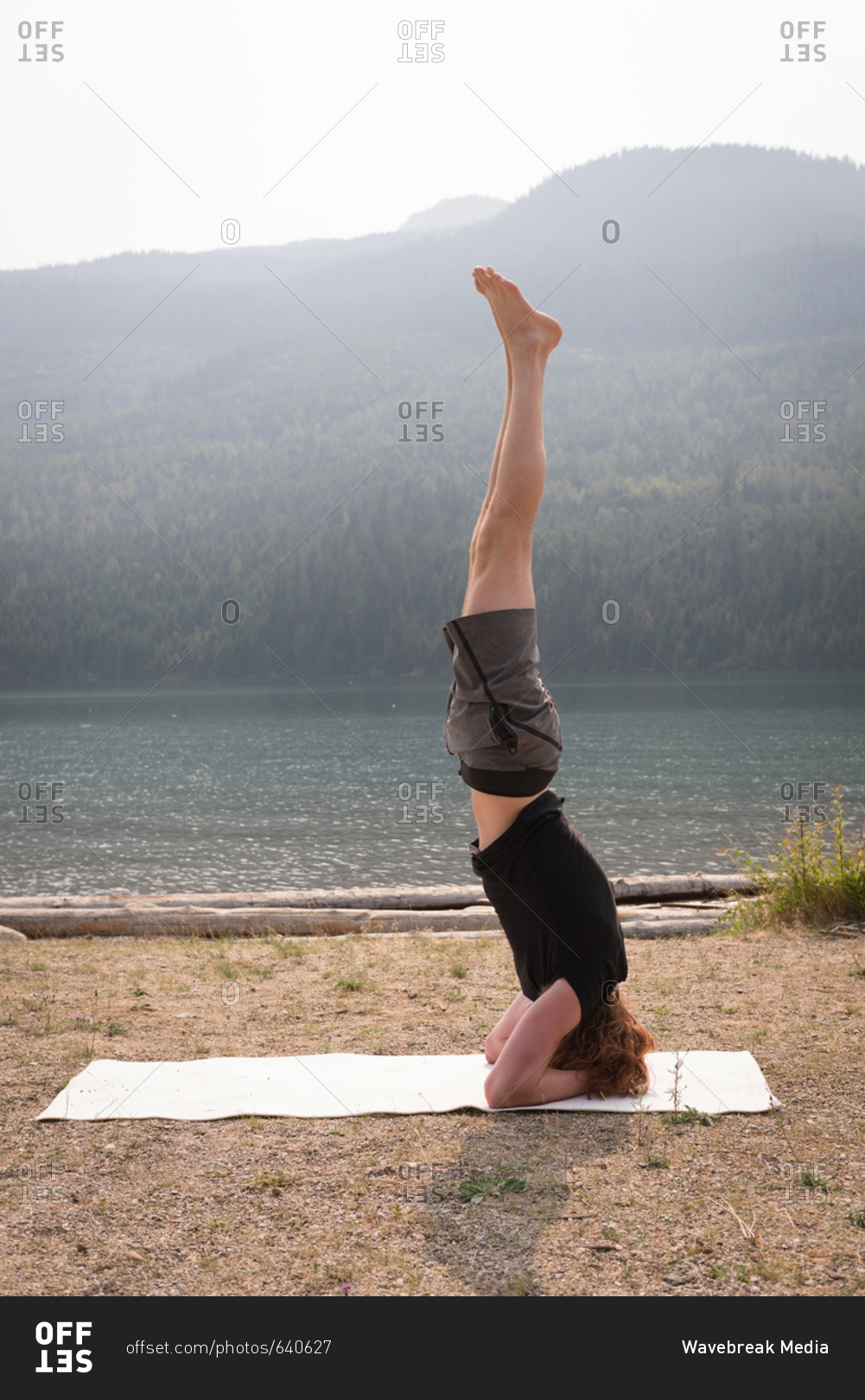 Sporty woman practicing head stand near the sea coast