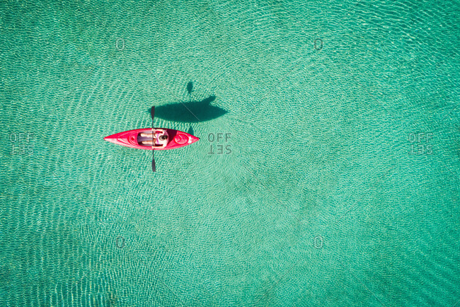 Kayaker kayaking in shallow turquoise water