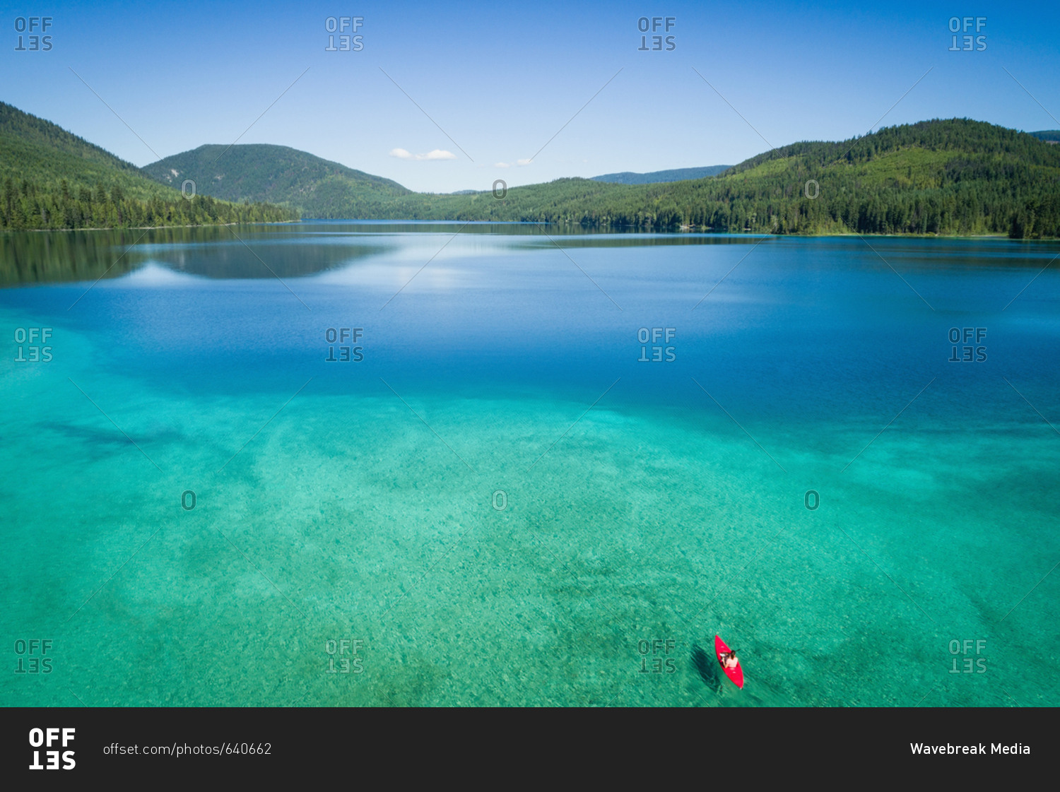 Kayaker kayaking in shallow turquoise water along the coastline