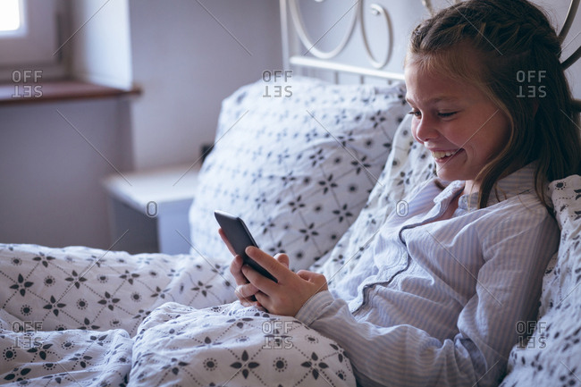 Girl using mobile phone on bed