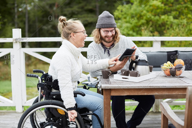 Young male caretaker and disabled woman using digital tablet in yard