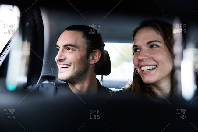 Smiling Young Friends Looking Through Window While Riding In Taxi