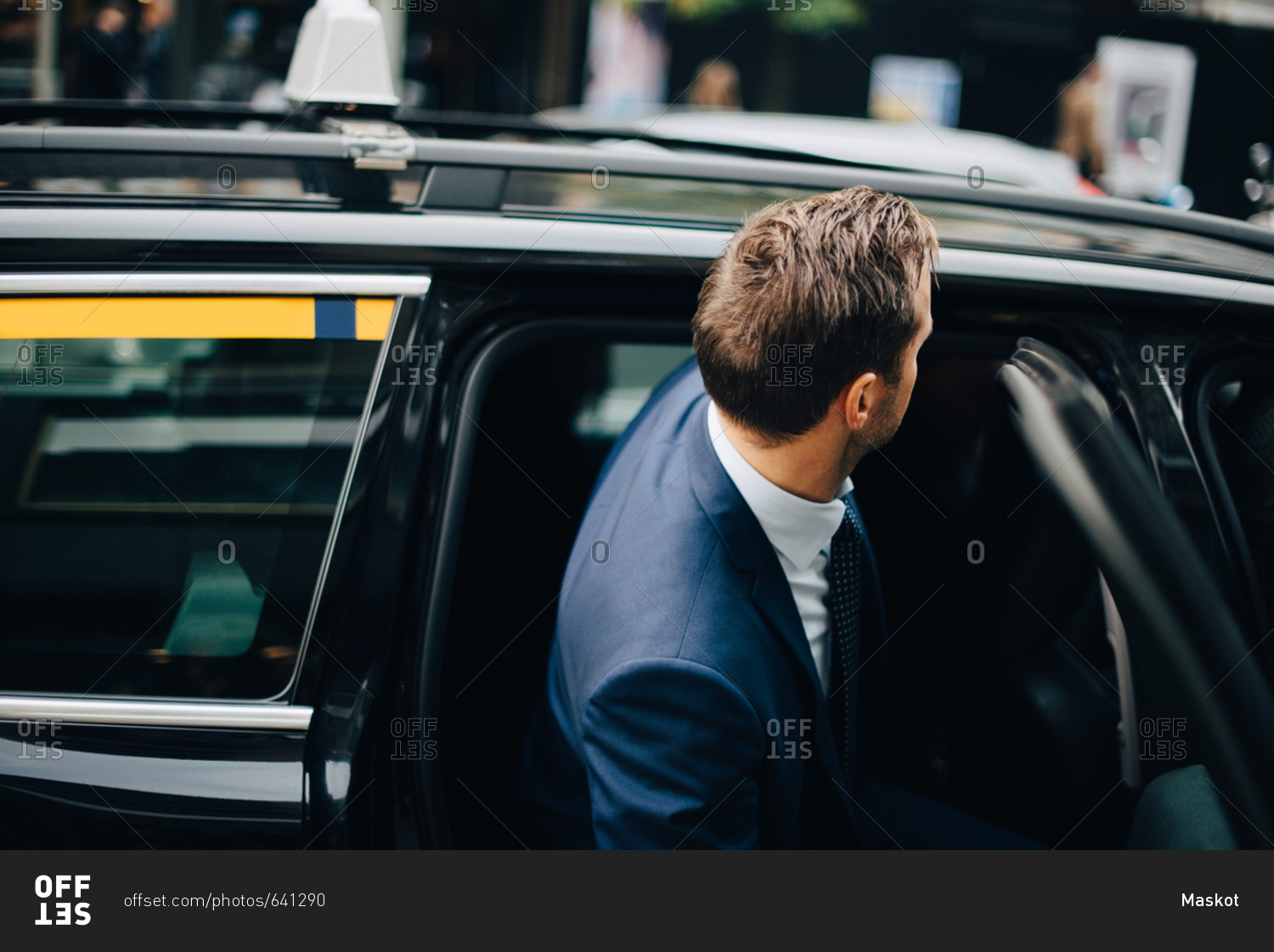 Side view of businessman entering taxi in city