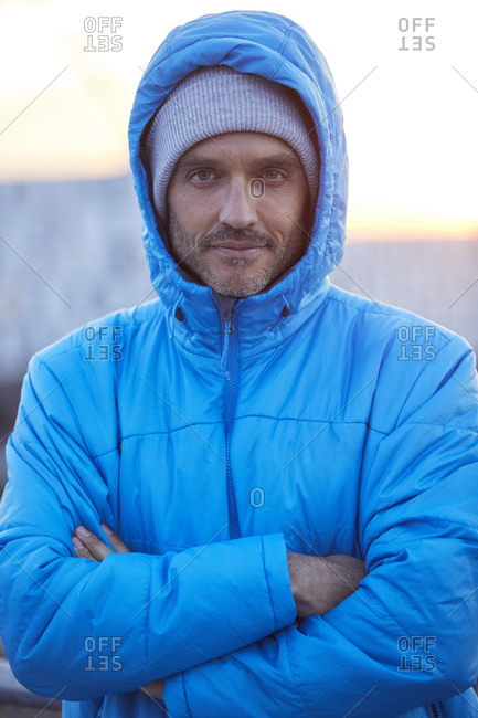 Portrait of confident man with hooded jacket and wooly hat in the city