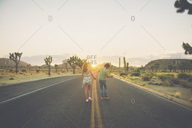 Hispanic couple holding hands walking in street