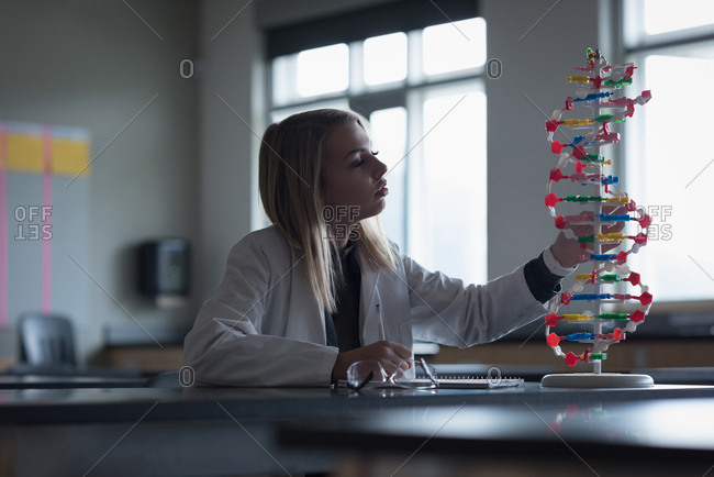 Teenage girl examining the molecule model in laboratory at university