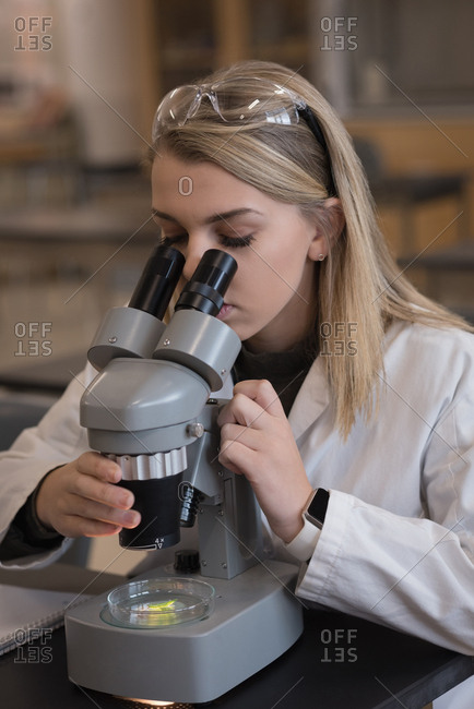 Teenage girl experimenting on microscope in laboratory at university