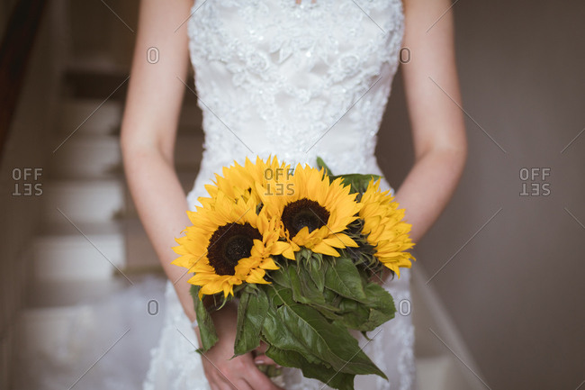 Mid section of bride holding a flower bouquet