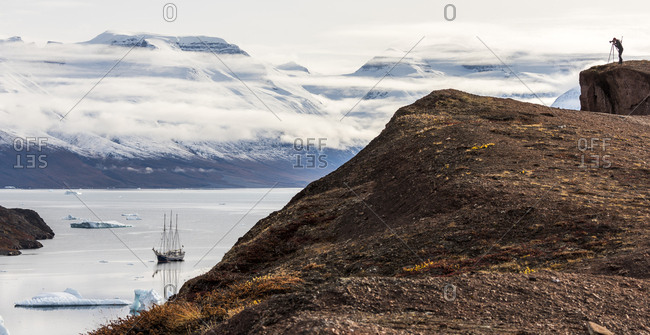 Greenland - December 22, 2017: Photographer taking picture of a sailboat in the Scoresby Sound in Greenland