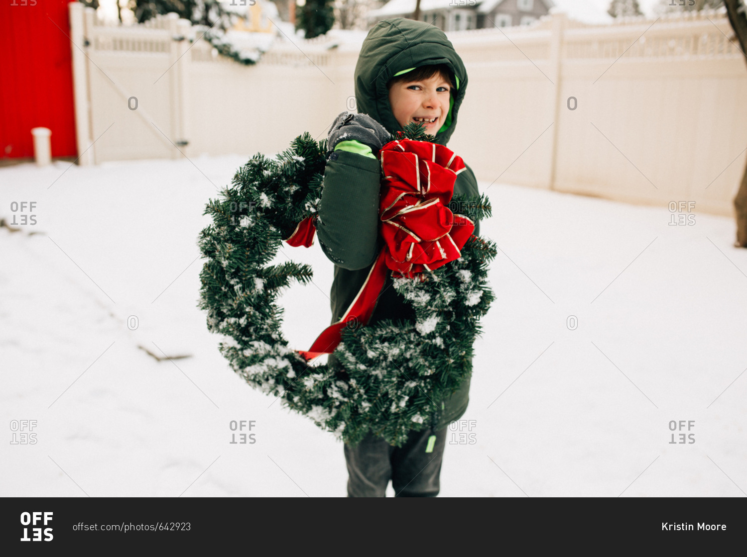 Kid carries Christmas wreath through snow