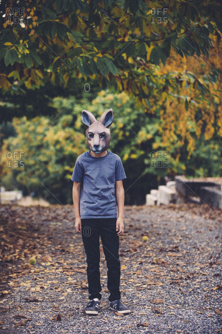 Full length of boy wearing animal mask while standing by trees during Halloween