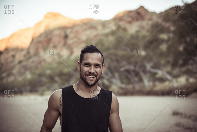 Portrait of smiling man standing against mountain at desert