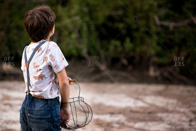 Rear view of boy holding a basket with fresh picked blackberry