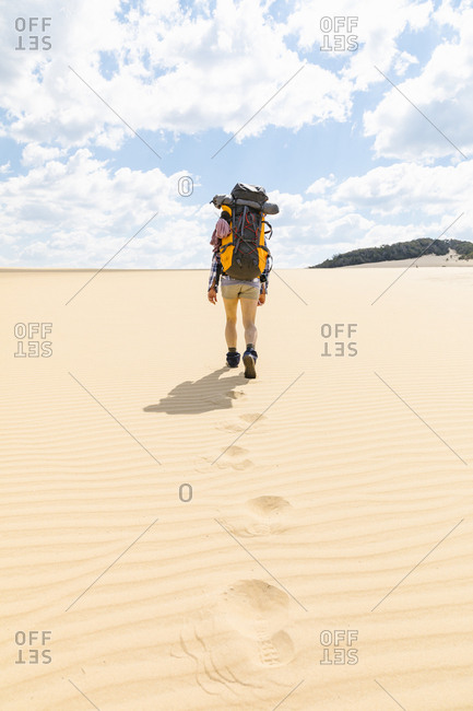 Rear view of woman hiking on sandy beach in Great Sandy National Park, Noosa Heads, Queensland, Australia