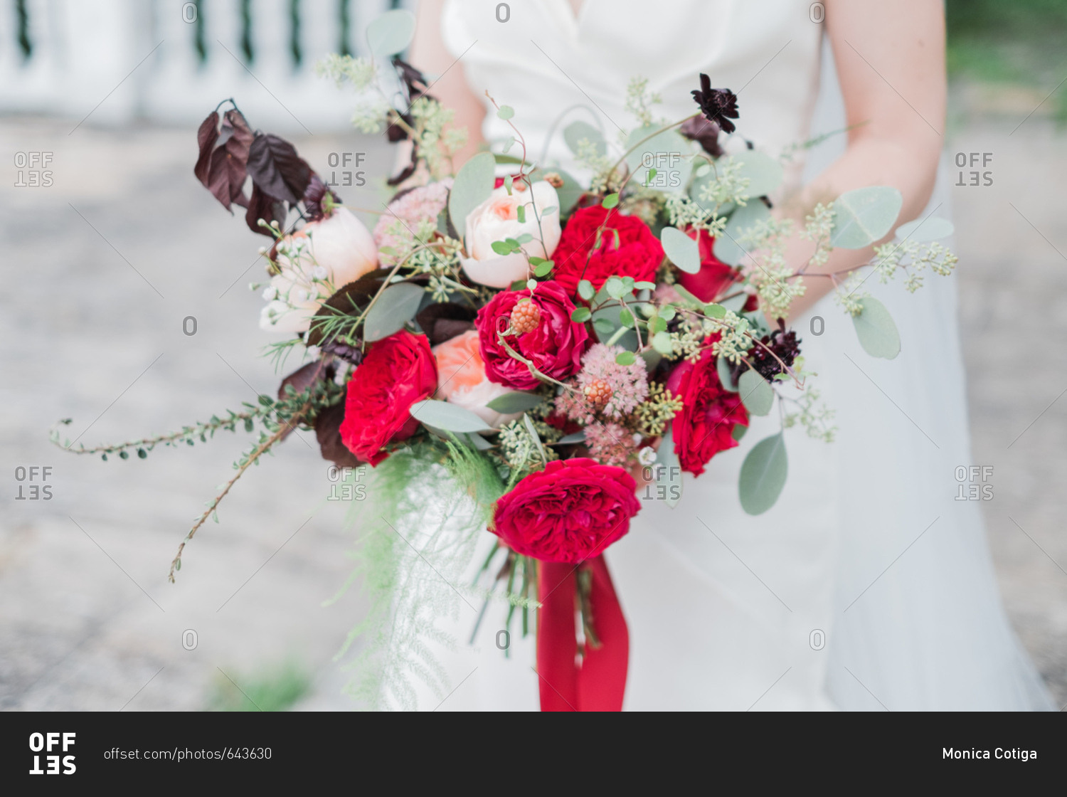 Close-up of bride holding wedding bouquet with red flowers