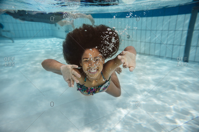 Girl swimming under water in swimming pool