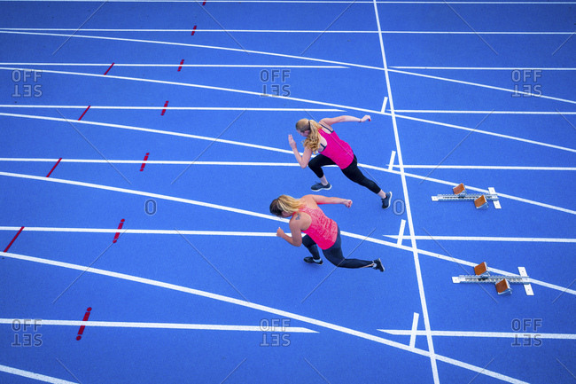 Top view of two female runners starting on tartan track