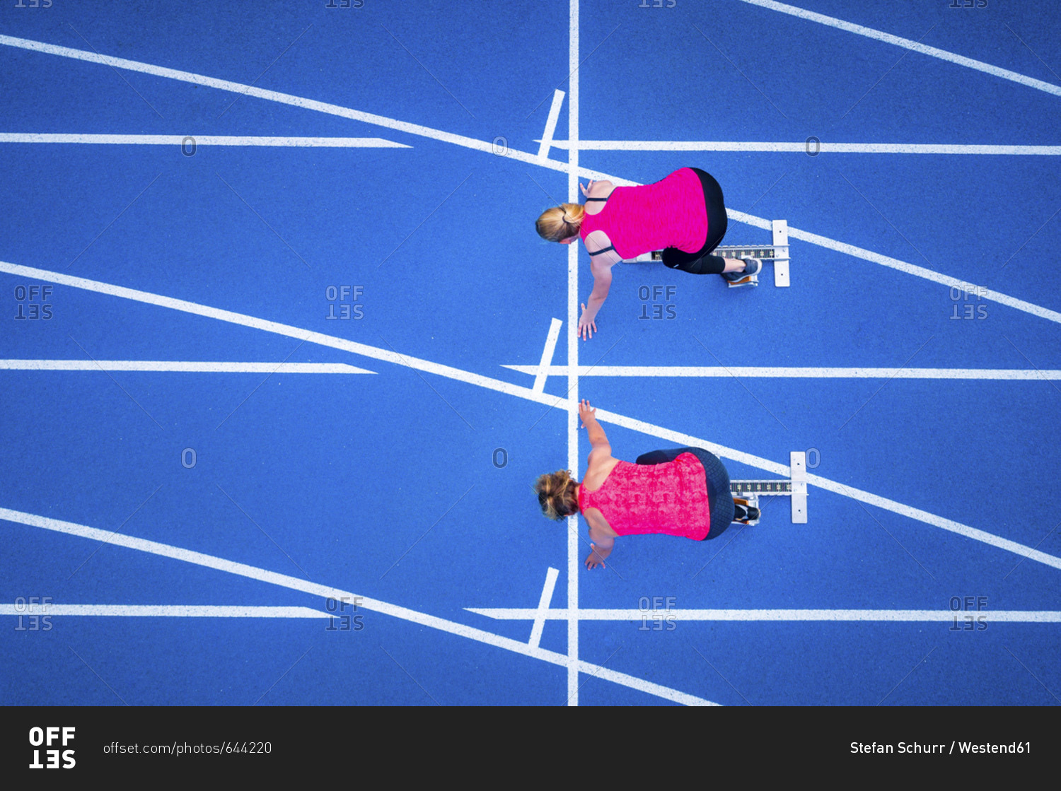 Top view of two female runners starting on tartan track
