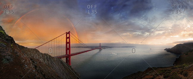 Panoramic view of the Golden Gate Bridge with a rainbow at sunset and orange-glowing storm clouds, San Francisco, California, United States, North America