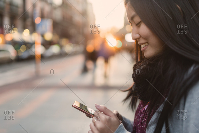 Asian woman browsing smartphone on street