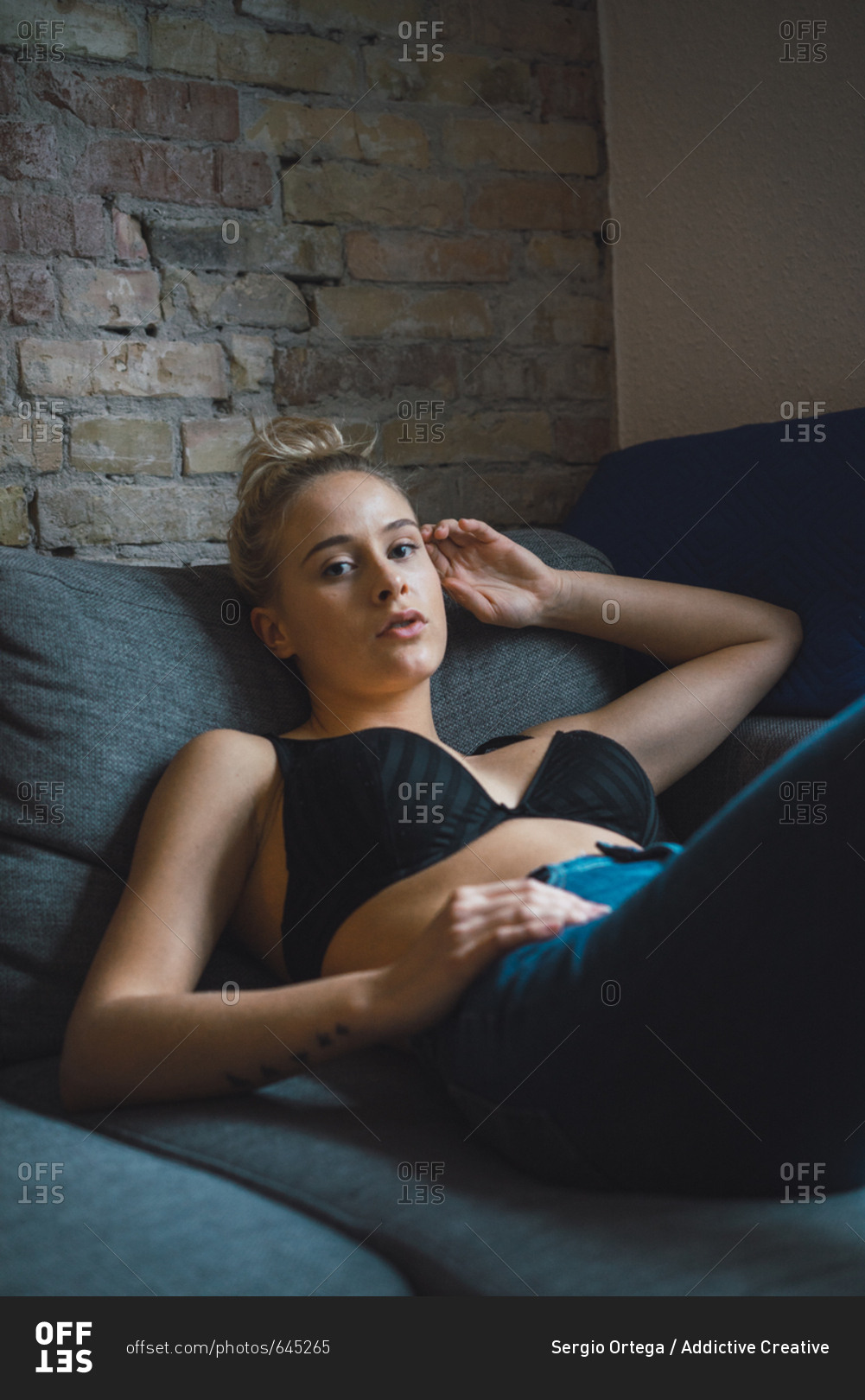 Woman in bra lying on bed stock photo - OFFSET