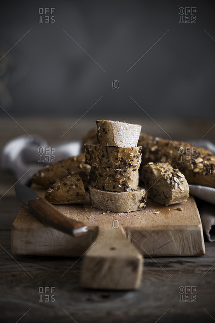 Slices of fresh cut bread lying near knife on wooden cutting board
