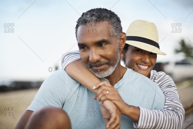 Mature couple relaxing happily together, wife leaning on her husband's back.