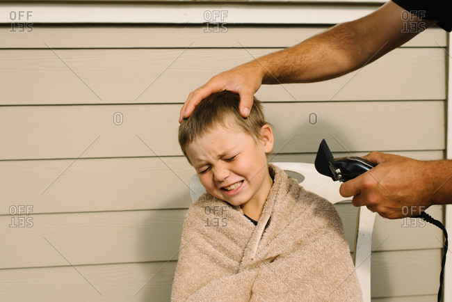 Person About To Use Clippers To Give Boy A Haircut Stock Photo