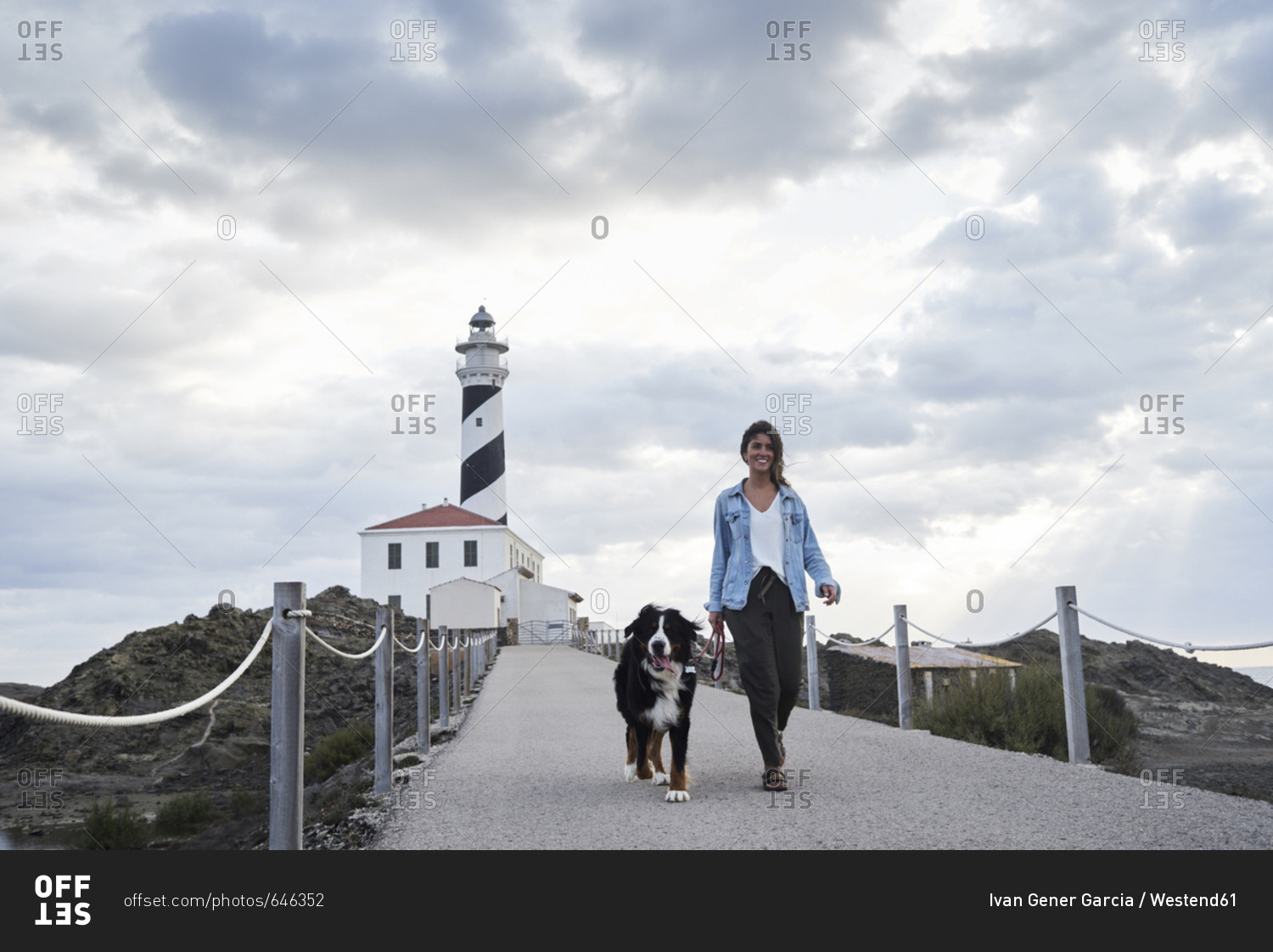 Spain- Menorca- Bernese mountain dog walking together with his owner outdoors at lighthouse
