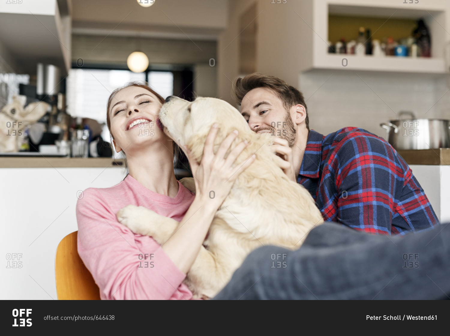 Happy young couple cuddling with dog at home