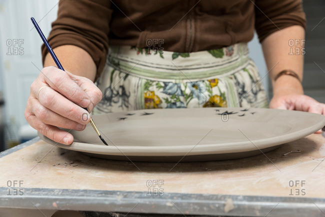 Potter painting motifs on platter