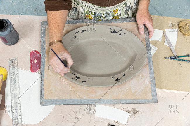 Potter painting motifs on platter