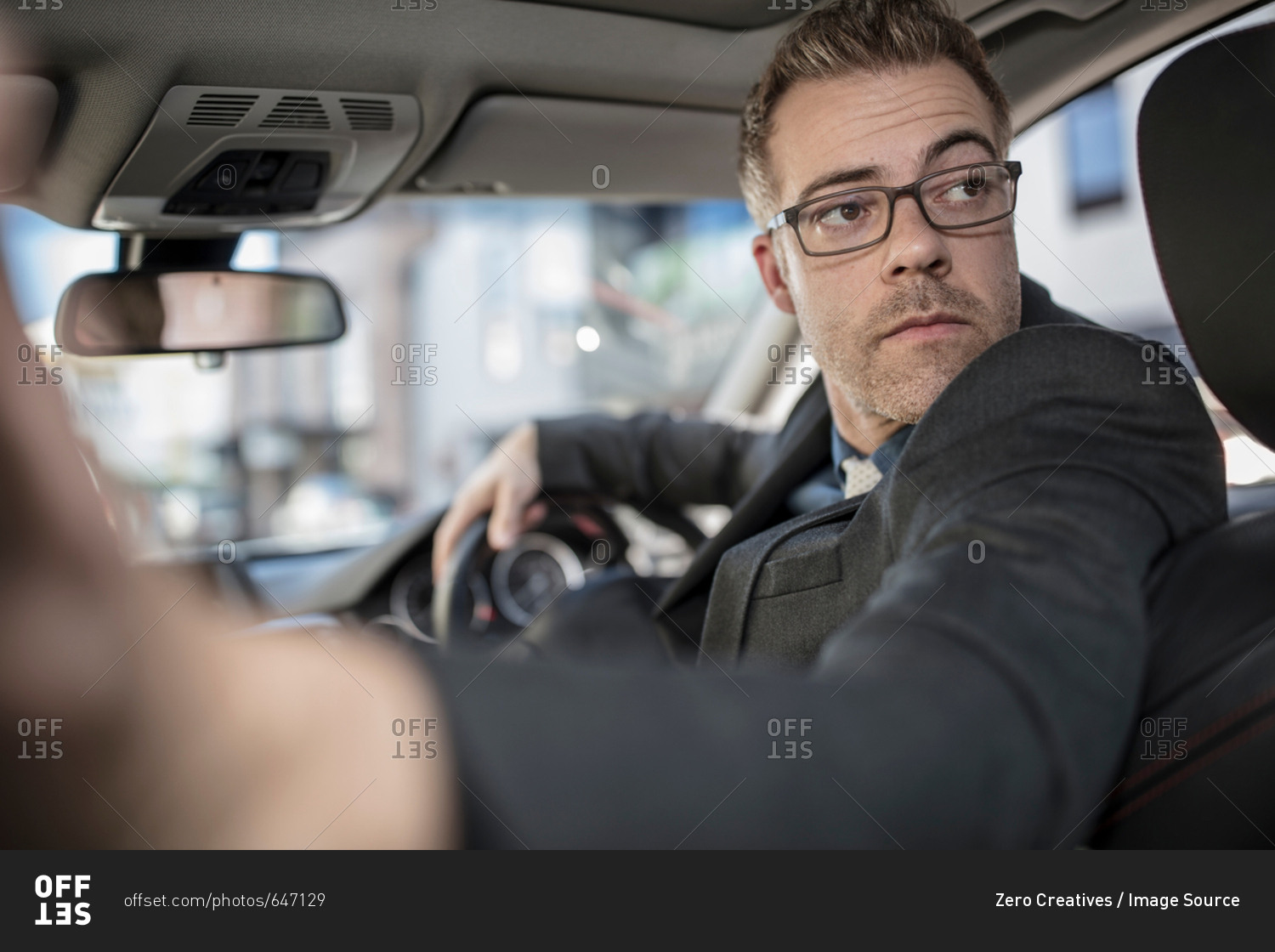 Businessman driving car, looking over shoulder, reversing