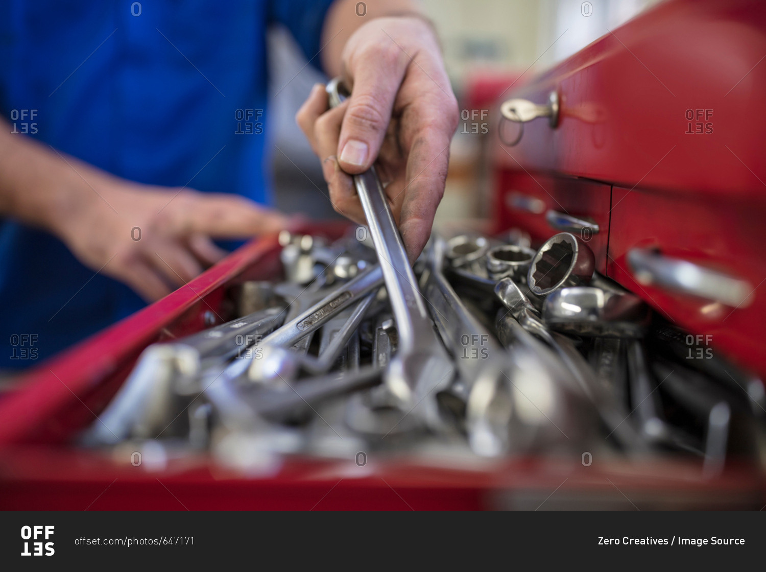 Hands of male car mechanic selecting wrench from tool box  in repair garage